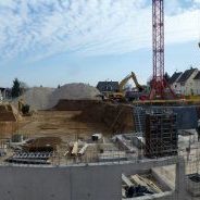 Baustelle eines mehrstöckigen Büro- und Verwaltungsgebäudes mit sichtbarer Bewehrung, Kran und Schalungssystemen im Rohbau