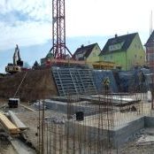 Baustelle eines mehrstöckigen Büro- und Verwaltungsgebäudes mit sichtbarer Bewehrung, Kran und Schalungssystemen im Rohbau